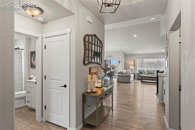 hall featuring recessed lighting, baseboards, and light wood-style floors