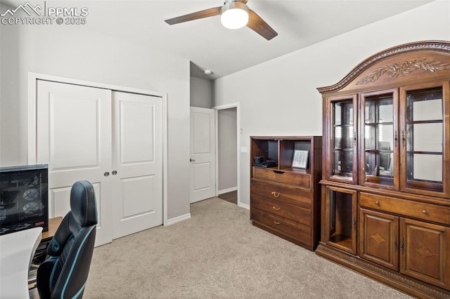 office space featuring light carpet, a ceiling fan, and baseboards
