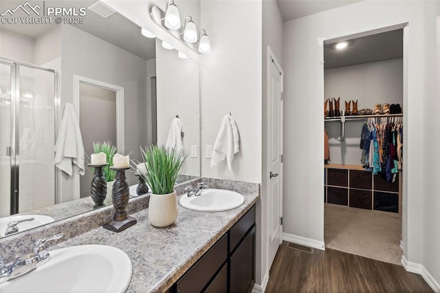 bathroom featuring baseboards, wood finished floors, a stall shower, and a sink