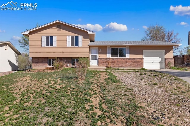 split level home with brick siding, an attached garage, and aphalt driveway