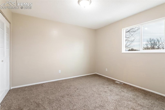 carpeted empty room featuring baseboards and visible vents
