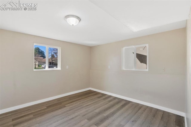 spare room featuring wood finished floors and baseboards