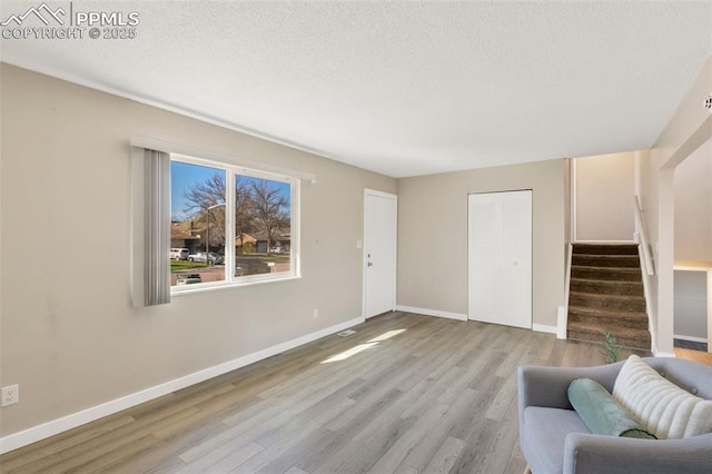 living room with baseboards, wood finished floors, a textured ceiling, and stairs