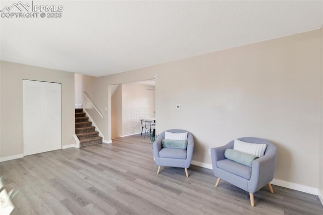 sitting room with light wood-style floors, stairway, and baseboards