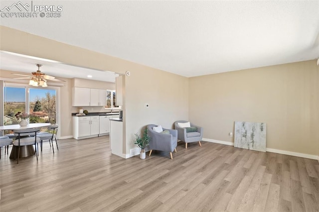 sitting room featuring baseboards, a ceiling fan, and light wood-style flooring