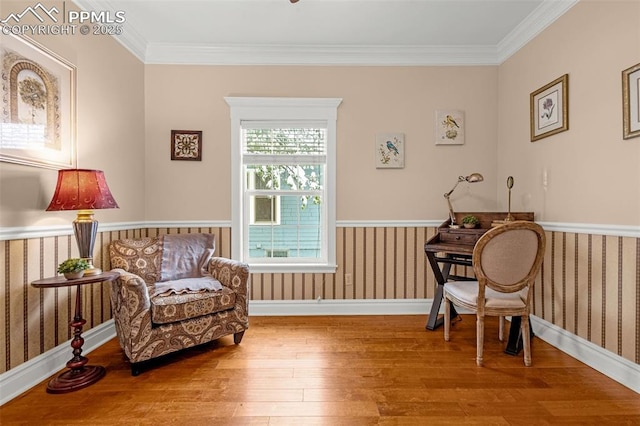 living area featuring baseboards, wainscoting, hardwood / wood-style flooring, and ornamental molding