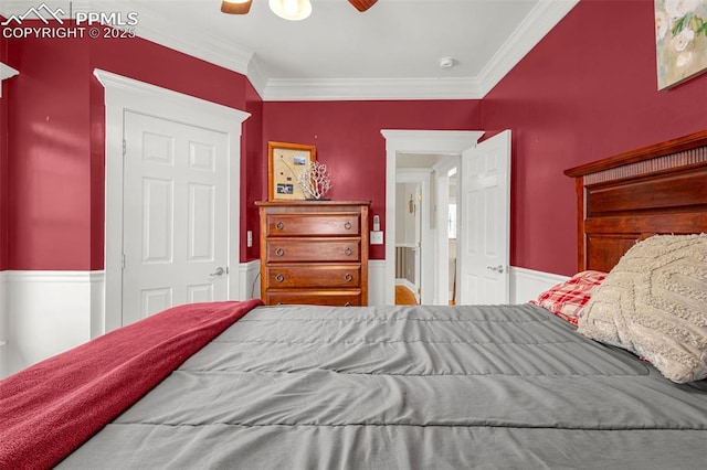 bedroom with ornamental molding, a wainscoted wall, and a ceiling fan