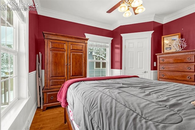 bedroom with wainscoting, wood finished floors, and ornamental molding
