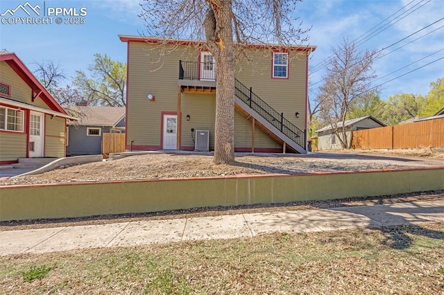 rear view of house featuring cooling unit, stairs, and fence
