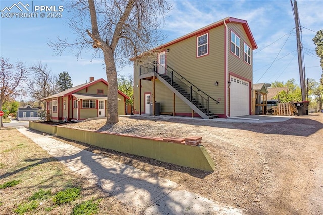 back of house featuring stairway, dirt driveway, and an attached garage