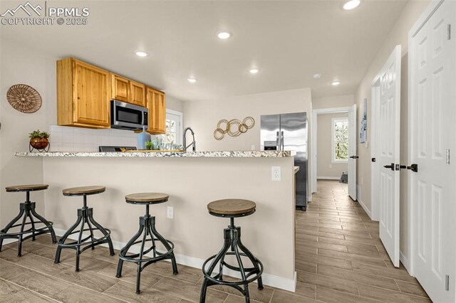 kitchen featuring wood tiled floor, recessed lighting, a sink, and appliances with stainless steel finishes
