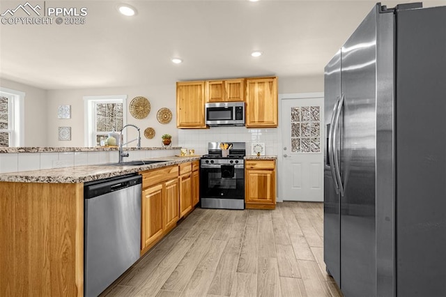 kitchen featuring a peninsula, a sink, appliances with stainless steel finishes, and a wealth of natural light