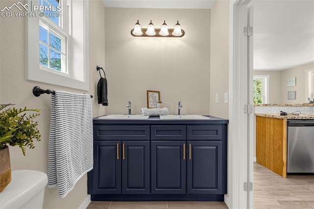 full bathroom with double vanity, toilet, baseboards, and a sink
