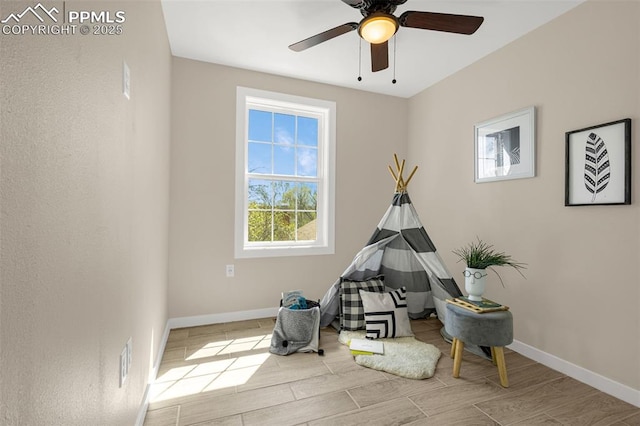 playroom featuring wood tiled floor, a ceiling fan, and baseboards
