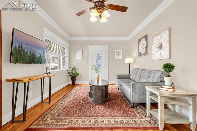 living area with crown molding, a ceiling fan, wood finished floors, and baseboards