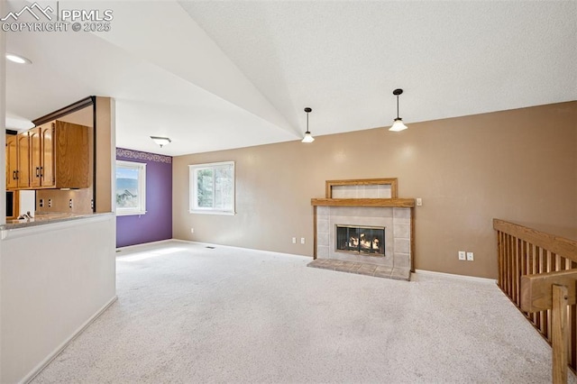 70 Palm Springs Dr, Colorado Springs, CO 80921 - unfurnished living room with light carpet, a tile fireplace, baseboards, and lofted ceiling