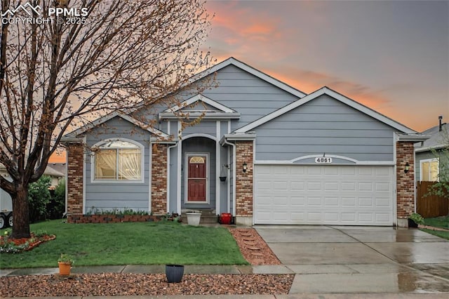 view of front of house featuring a garage, concrete driveway, a front lawn, and brick siding
