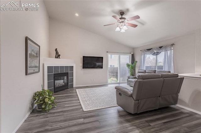 living room with vaulted ceiling, a ceiling fan, dark wood-style floors, a fireplace, and baseboards