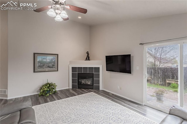 unfurnished living room featuring wood finished floors, a ceiling fan, baseboards, a fireplace, and recessed lighting