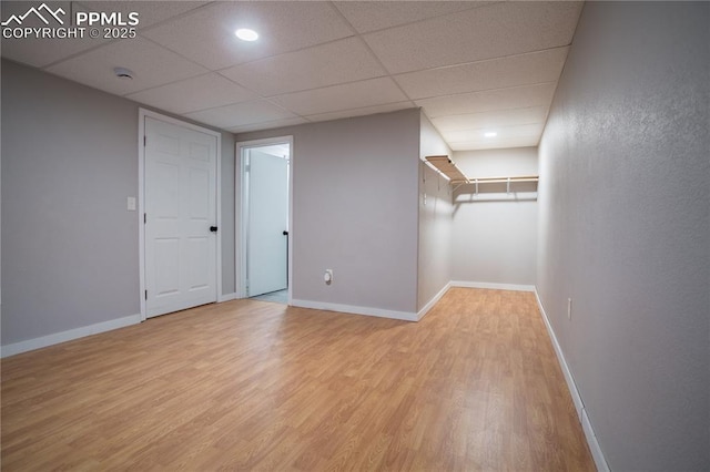 finished below grade area featuring wood finished floors, baseboards, and a paneled ceiling