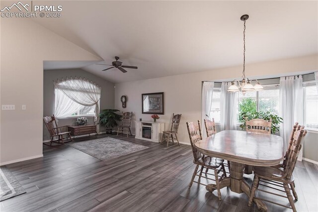 dining area with vaulted ceiling, wood finished floors, a chandelier, a ceiling fan, and baseboards