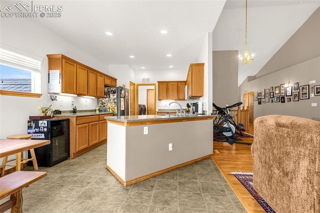 kitchen featuring brown cabinetry, wine cooler, freestanding refrigerator, and an inviting chandelier