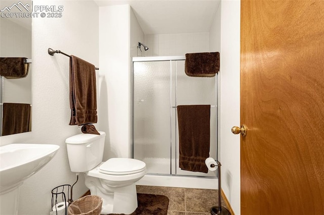 bathroom with toilet, tile patterned flooring, and a stall shower