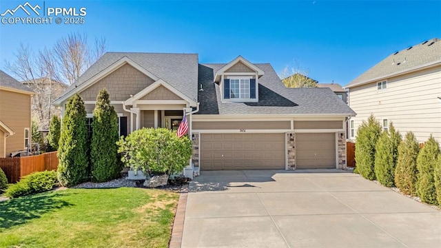 craftsman-style home with fence, a shingled roof, an attached garage, driveway, and a front yard