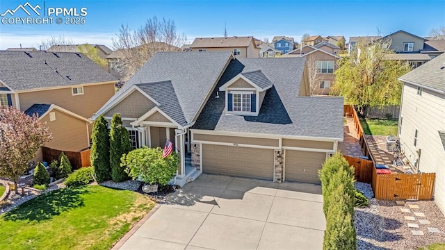 craftsman-style house with fence, a residential view, an attached garage, driveway, and roof with shingles