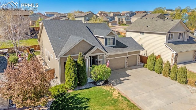 view of front facade featuring a residential view, an attached garage, a shingled roof, and driveway