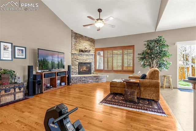 living room featuring a stone fireplace, wood finished floors, high vaulted ceiling, and ceiling fan