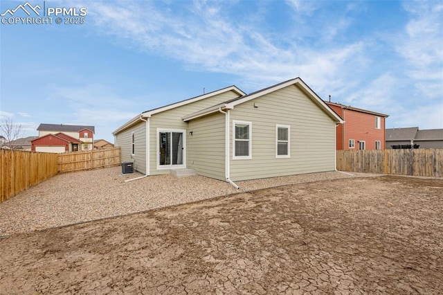 back of property with a fenced backyard and central AC unit