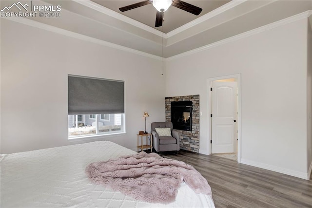 bedroom with ceiling fan, crown molding, wood finished floors, baseboards, and a tray ceiling