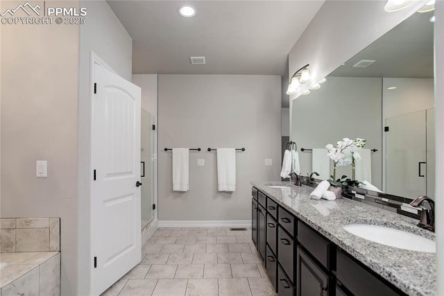 bathroom with double vanity, baseboards, a shower stall, and a sink