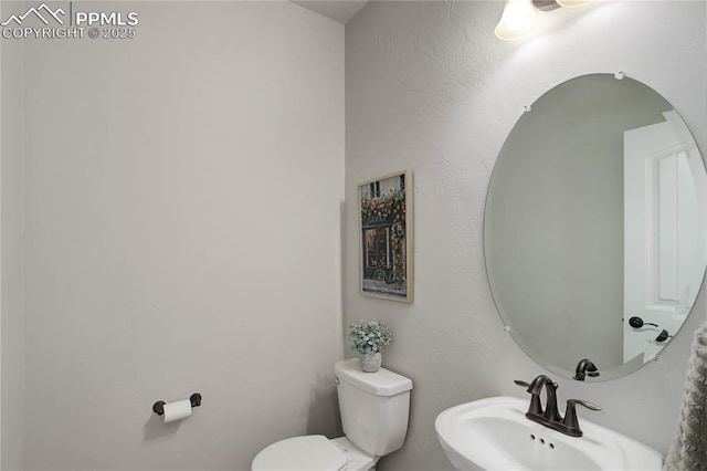 half bathroom featuring toilet and a sink