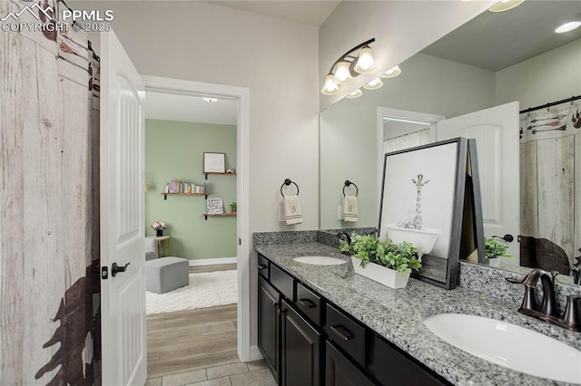 full bathroom featuring double vanity, a sink, baseboards, and tile patterned floors