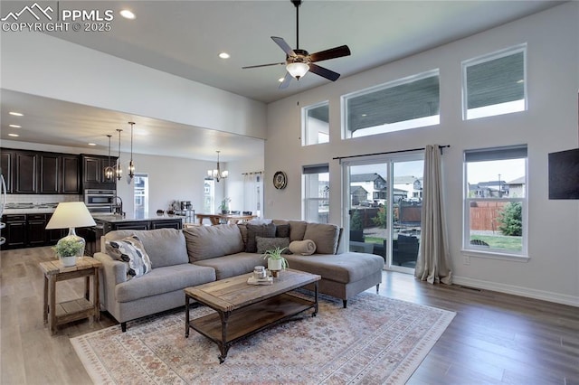living room featuring a healthy amount of sunlight, a high ceiling, ceiling fan with notable chandelier, and recessed lighting