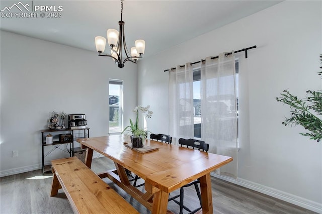 dining space featuring an inviting chandelier, baseboards, and wood finished floors