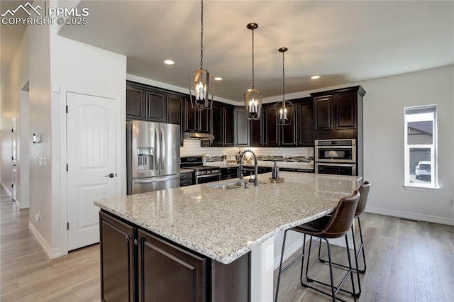 10704 Shavano Peak Ct, Peyton, CO 80831 - kitchen featuring baseboards, light wood-style floors, tasteful backsplash, and stainless steel appliances