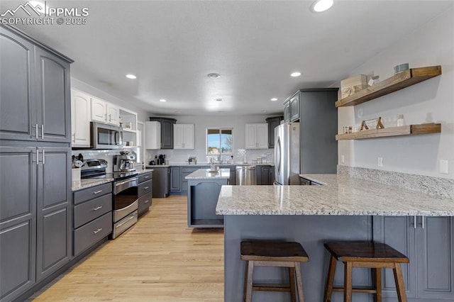 15930 Alta Plaza Cir, Peyton, CO 80831 - kitchen featuring stainless steel appliances, open shelves, a peninsula, a kitchen bar, and light stone counters