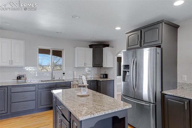 15930 Alta Plaza Cir, Peyton, CO 80831 - kitchen with stainless steel appliances, arched walkways, light wood finished floors, light stone countertops, and recessed lighting