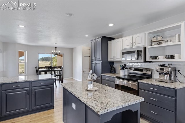 15930 Alta Plaza Cir, Peyton, CO 80831 - kitchen with stainless steel appliances, a kitchen island, backsplash, light stone counters, and a chandelier
