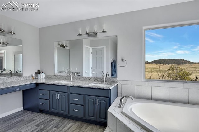 15930 Alta Plaza Cir, Peyton, CO 80831 - bathroom with double vanity, a garden tub, and wood finished floors