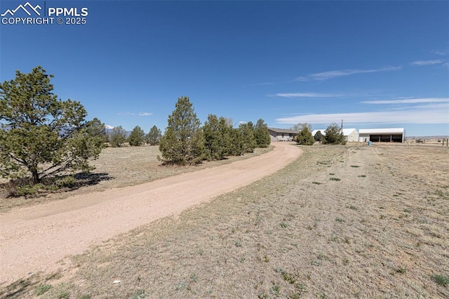 view of road featuring a rural view and dirt driveway