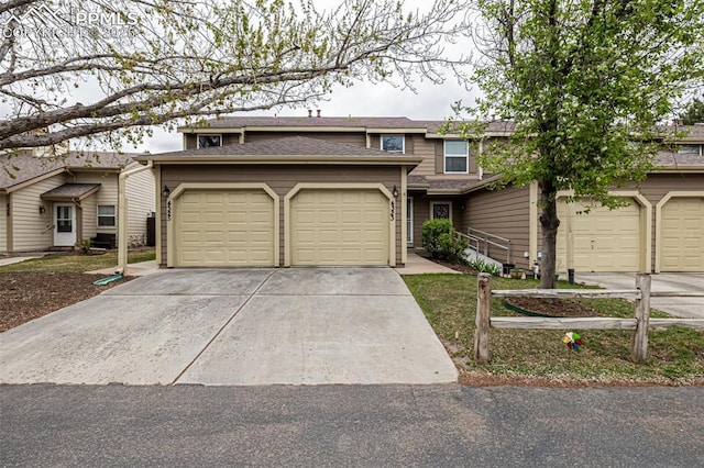 view of front of house with concrete driveway, an attached garage, and roof with shingles
