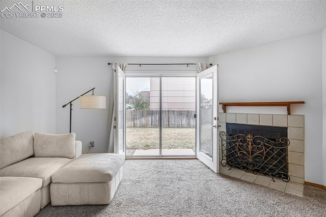 living area with a tile fireplace, carpet flooring, and a textured ceiling
