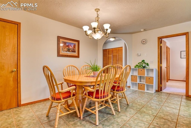 dining room with arched walkways, a textured ceiling, a chandelier, and light tile patterned floors