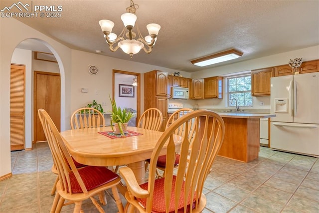 dining room with arched walkways, a textured ceiling, an inviting chandelier, and light tile patterned flooring