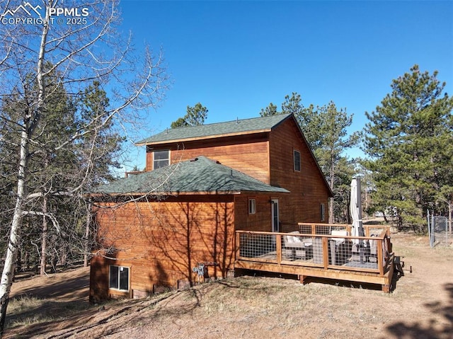 view of side of home featuring a wooden deck and a shingled roof