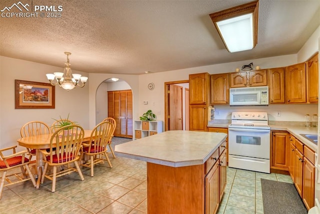 kitchen with light countertops, white appliances, arched walkways, and a kitchen island